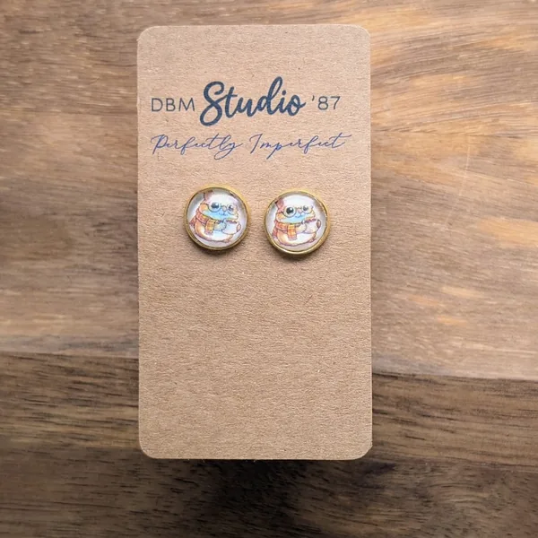 small round glass cabochon earrings in gold tone. An image of a cartoon hampster wearing glasses, with a scarf holding a coffee inside.